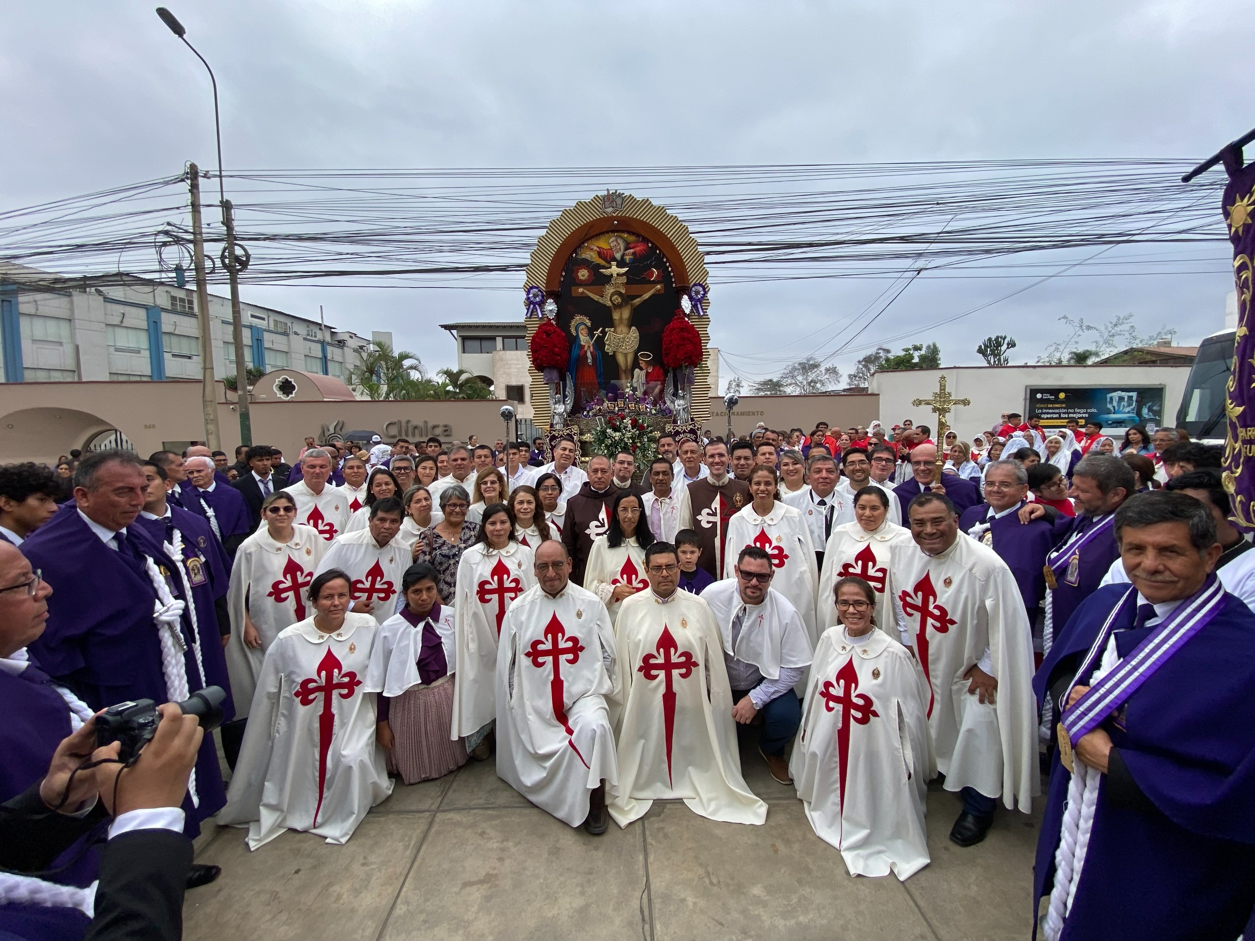 Les Hérauts de l'Évangile, en cape blanche à croix rouge et en habit brun, posent avec des porteurs en habit violet devant la réplique du brancard du Seigneur des Miracles, à Lima