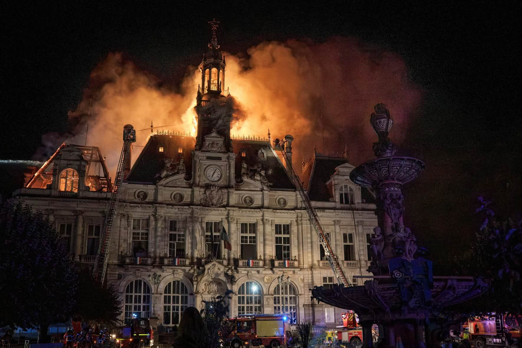 L'hôtel de ville de Limoges en flammes, la nuit, avec des pompiers sur des échelles devant la façade